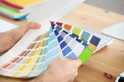 Person comparing color swatches for design project.