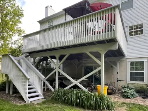 White house with elevated deck and stairs.